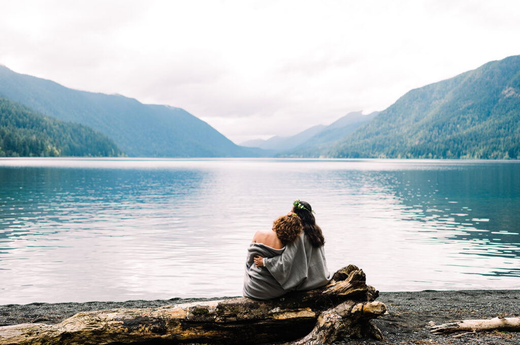 Couple sitting on beach at Lake Crescent in Washington State